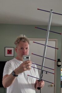 A tired looking guy holds up a Yagi antenna