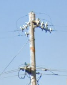 The top of a utility pole featuring antiquated, sagging insulators.